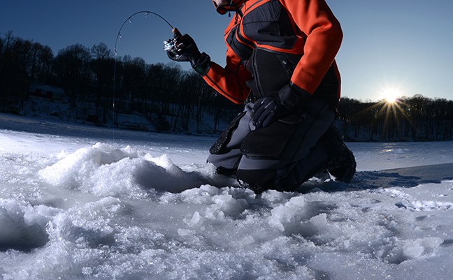 A man on the ice fishing in the finger lakes early morning 