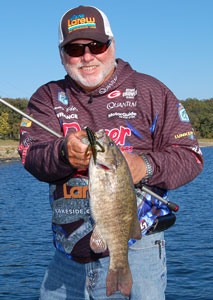 A bearded pro angler holding a smallmouth bass