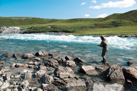 A fly angler fishing the edge of a fast, blue-water stretch of river.