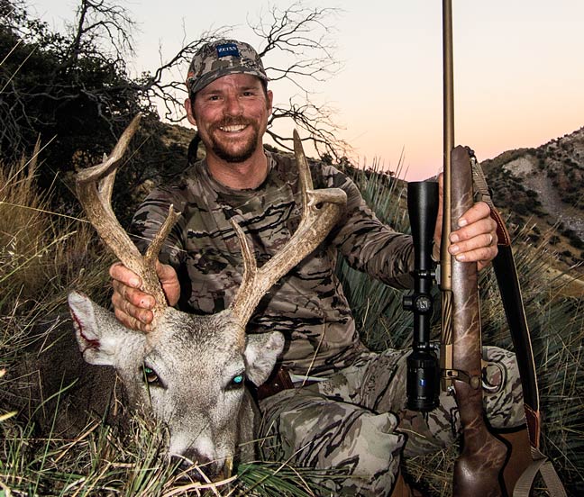 hunter posing with buck and rifle