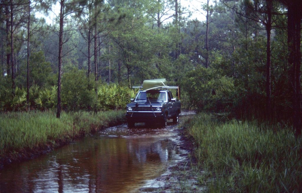 truck driving through flooded trail in the woods